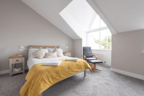 ポーツチュワートにあるThe Strand Mewsのベッドルーム1室(黄色い毛布と椅子付きのベッド1台付)