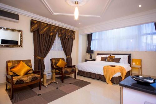 a hotel room with a bed and two chairs at The Ritzz Exclusive Guest House in Accra