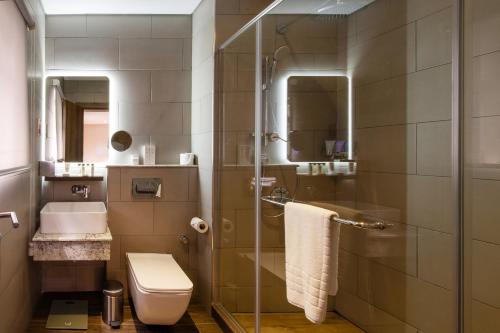 a bathroom with a shower and a toilet and a sink at The White Orchid Hotel in Lagos