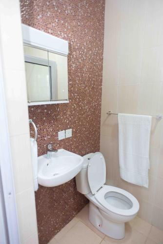 a bathroom with a toilet and a sink and a mirror at The Ritzz Exclusive Guest House in Accra