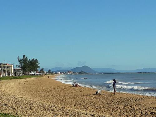 a person standing on a beach with a dog at Hospedagem da Rose in Marataizes