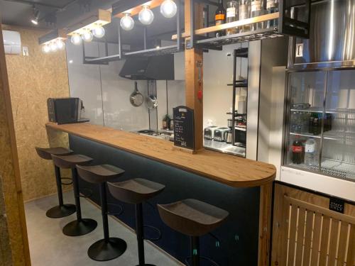 a kitchen with a counter with stools at a bar at Arura Sapporo in Sapporo