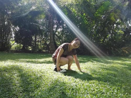 a woman squatting in the grass with aploadploadploadploadploadploadpload at Old Parkland Hostel in Galle