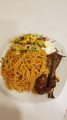 a plate of noodles and meat on a white plate at Private Executive Apartments in Accra