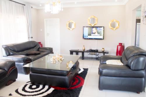 - un salon doté d'un mobilier en cuir et d'une table dans l'établissement Villa Prince, à Harare