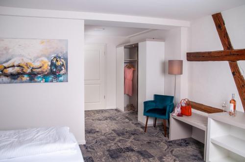a bedroom with a bed and a desk and a blue chair at Hotel Schuberths am Schloss in Buttenheim