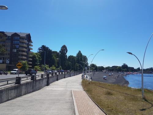 a sidewalk next to a beach with people on it at Depto primera línea de playa para 5 personas in Villarrica