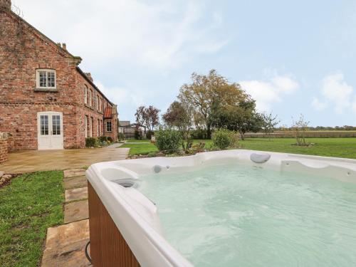 a hot tub in a yard next to a brick building at Copmanthorpe Hall in York
