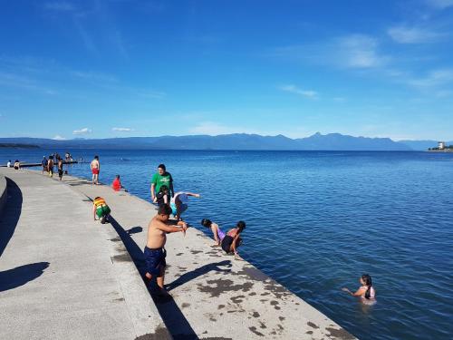 a group of people playing in the water at a lake at Depto primera línea de playa para 5 personas in Villarrica