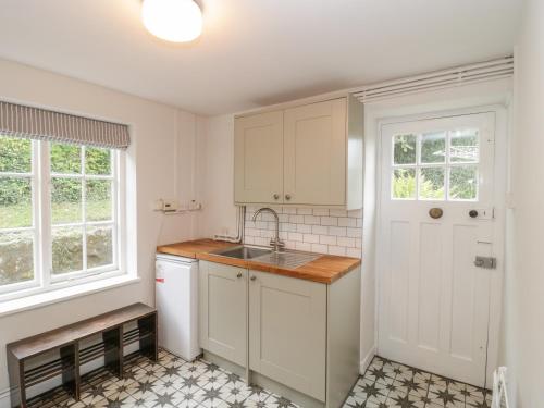 a kitchen with white cabinets and a sink and a window at Church View in Tisbury