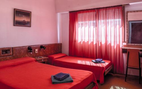 una habitación de hotel con 2 camas y cortinas rojas en Hotel La Argentina en San Bernardo