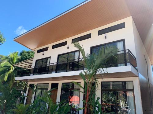 a white house with black windows and palm trees at Hotel Manuel Antonio Park in Manuel Antonio