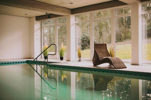 ein Haus mit einem Pool mit Stühlen und Fenstern in der Unterkunft Hotel Zur Burg Sternberg in Extertal