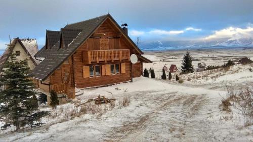 a large wooden house in the snow with a road at Kiwi Chalet in Kupres