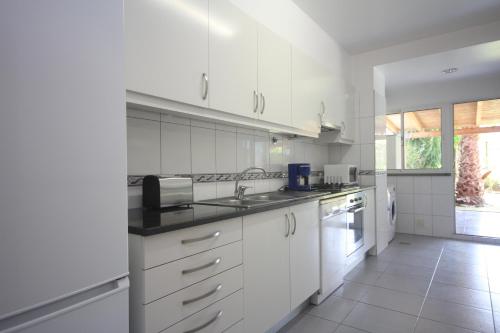 eine weiße Küche mit weißen Schränken und einem Waschbecken in der Unterkunft Atlantic Palm Garden Residence in Caniço