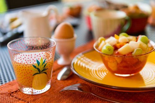a plate with a bowl of fruit and a cup of juice at Mas Du Roc Bed & Breakfast in Grasse