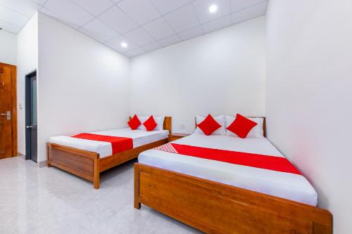 2 Betten mit roten Kissen in einem Zimmer in der Unterkunft OYO 745 Minh Duc Guest House in Nha Trang