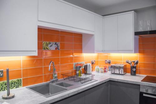 a kitchen with a sink and an orange tiled wall at higgihaus #3a 4 Bed Sleeps up to 12 Big Groups Hip Location in Bristol