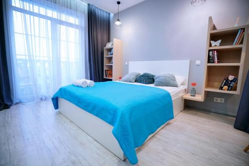 a bedroom with a bed with a blue blanket on it at British Quarter Studios in Kyiv