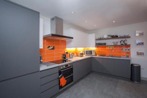 a large kitchen with orange tiles on the wall at higgihaus #3b 4 Bed Sleeps up to 10 Big Groups Hip Location in Bristol