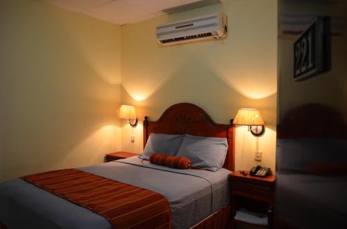 a bedroom with a bed with two lamps and a fan at Hotel Plaza Palmero in San Pedro Sula
