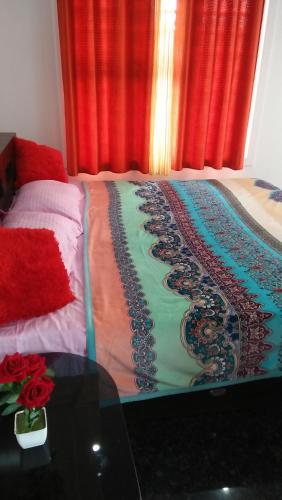 a bedroom with a bed with a table and red curtains at Chamayam Holiday Villa in Meenangadi