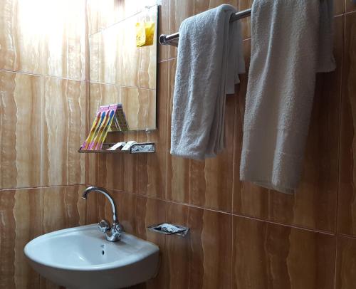 a bathroom with a sink and a mirror and towels at Hotel Hill View in Bāndarban