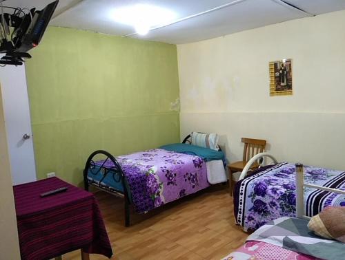 a room with two beds and a table in it at Hotel Sueños del Chuncho in Yauyos