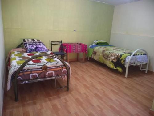 Habitación con suelo de madera y 2 camas. en Hotel Sueños del Chuncho en Yauyos