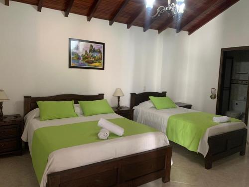 a bedroom with two beds with green sheets at Hotel Las Nieves in Girón