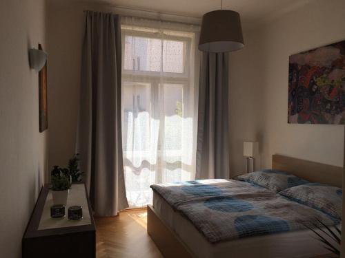 a bedroom with a bed and a large window at Apartment Náměstí Bratří Synků in Prague