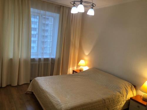 ein Schlafzimmer mit einem Bett, einem Fenster und zwei Lampen in der Unterkunft Затишна 2х кімнатна квартира біля метро Академмістечко in Kiew