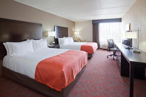 a hotel room with two beds and a desk at Holiday Inn Express & Suites Bloomington West by IHG in Bloomington
