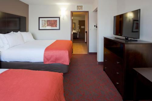 a hotel room with two beds and a flat screen tv at Holiday Inn Express & Suites Bloomington West by IHG in Bloomington