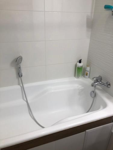 La salle de bains est pourvue d'une baignoire blanche avec un robinet. dans l'établissement Затишна 2х кімнатна квартира біля метро Академмістечко, à Kiev