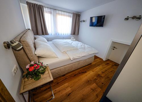 a small bedroom with a bed and a table with flowers at Appartements Römerhof Superior - Kärnten Card im Sommer inklusive in Bad Kleinkirchheim