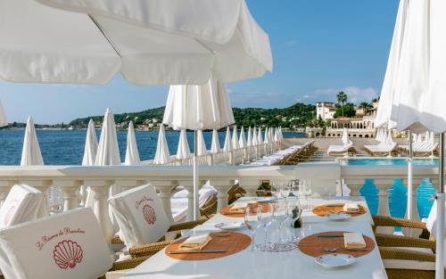 a restaurant with white tables and white umbrellas on a cruise ship at La Réserve de Beaulieu in Beaulieu-sur-Mer