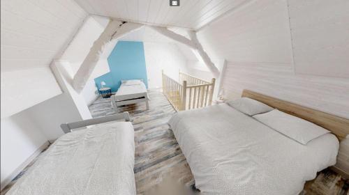 een slaapkamer met 2 bedden in een witte kamer bij Charmante petite maison de la côte Normande in Courseulles-sur-Mer