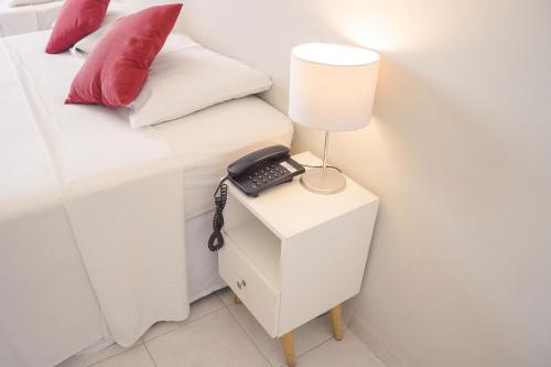 
a white bed sitting next to a white lamp at CLH Suites Domingos Ferreira in Rio de Janeiro
