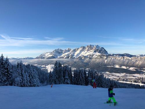 a child on skis in the snow in front of a mountain at Berghof Haselsberger in Sankt Johann in Tirol