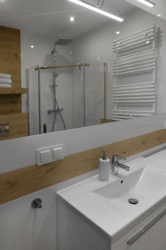 Baño blanco con lavabo y espejo en Apartament Szary Wilk en Świeradów-Zdrój