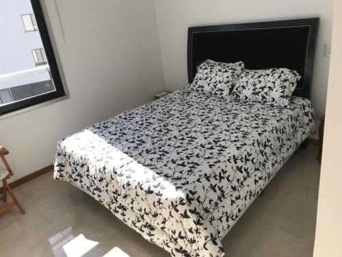 uma cama com um edredão e almofadas preto e branco em Residencias Pilar Golf Edificio Doral em Fátima