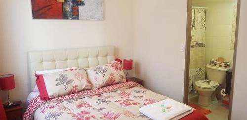 1 dormitorio con 1 cama con sábanas rosas y blancas en Departamento a pasos del Faro, en La Serena