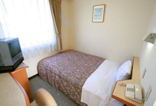 a hotel room with a bed and a desk and a television at Star Hotel Koriyama in Koriyama