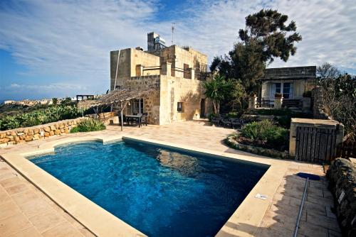 a swimming pool in front of a house at Dar Ix-Xemx in Nadur