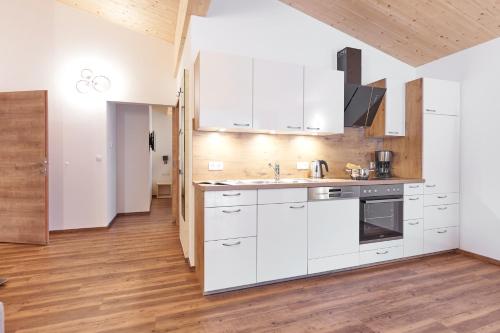 a kitchen with white cabinets and a wooden floor at Appartement Fritz inkl Summer Card in Umhausen
