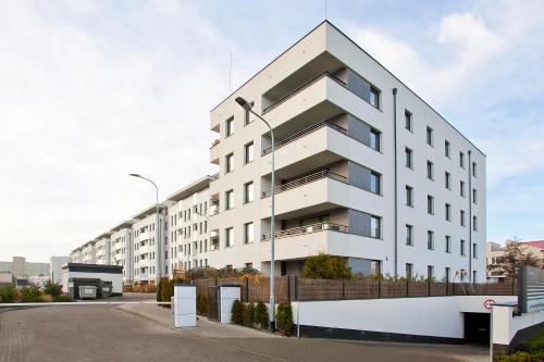 a white apartment building with a parking lot at Elite Apartments Marine Suite in Gdańsk