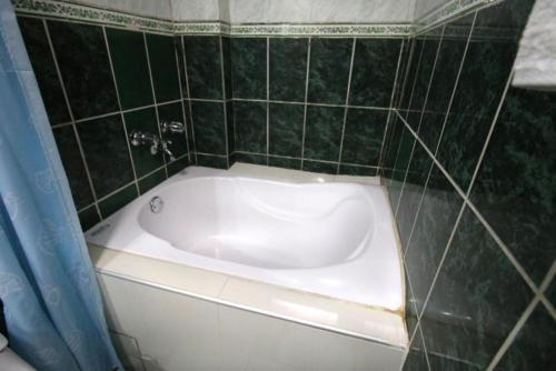 a bath tub in a bathroom with green tiles at Hotel Peru Real in Cusco