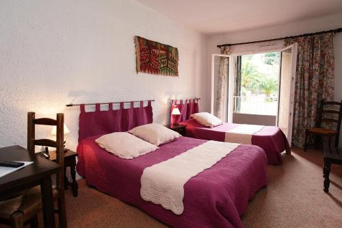 a bedroom with two beds and a desk and a window at Motel le Colibri in Lucciana
