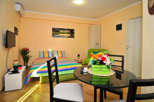 ein Wohnzimmer mit einem Bett und einem Tisch mit Blumen in der Unterkunft Apartments M&T in Tivat